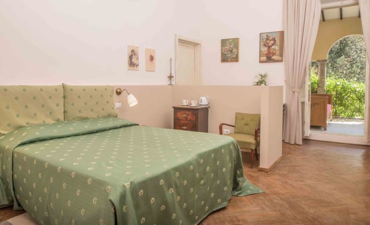Renovated room featuring historical elements with a view of the surrounding green area.