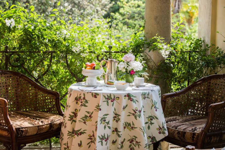 An outdoor breakfast table set surrounded by plants and flowers in the garden.