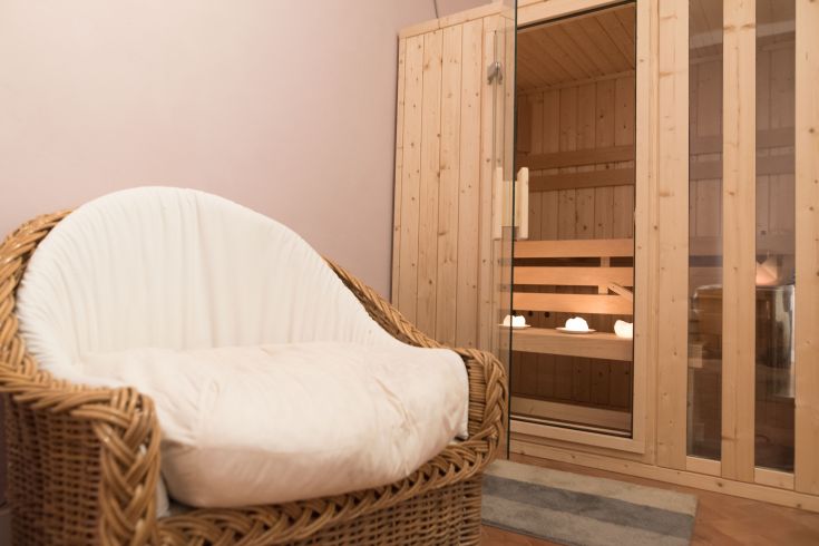 A wellness area featuring a wooden sauna and a cozy chair.