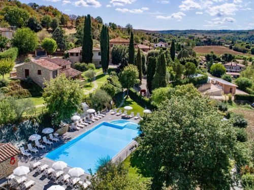 Green farmhouse surrounded by lush hills, featuring an outdoor pool in a peaceful natural setting.