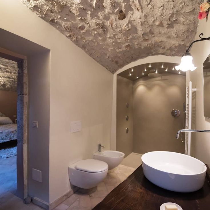 Modern bathroom interior with light walls and exposed stone ceiling.