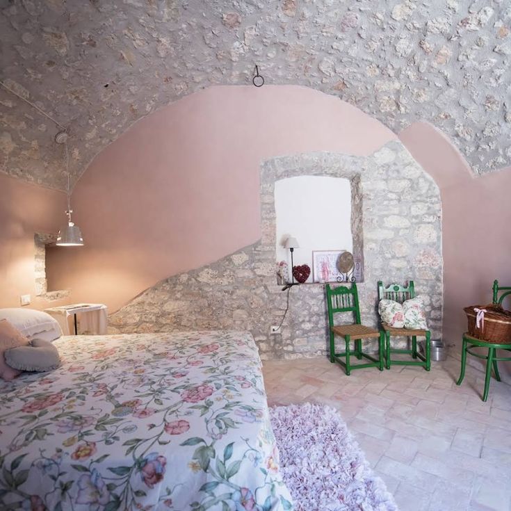 A cozy bedroom with stone walls and simple floral decorations.