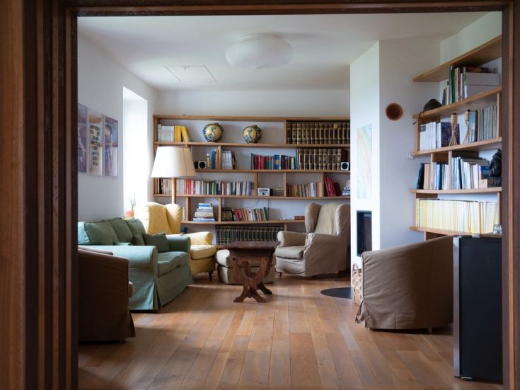 A simple living room with a bookshelf, colorful sofas, and decorative elements, perfect for relaxation.
