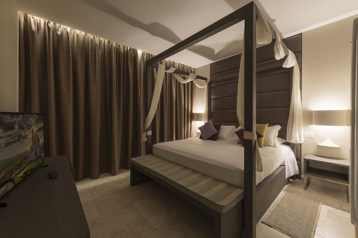 Camera con letto a baldacchino, luce calda e TV, adatta per un soggiorno confortevole.