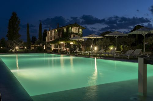 Une villa avec une piscine éclairée crée une ambiance calme et accueillante lors d'une soirée d'été.