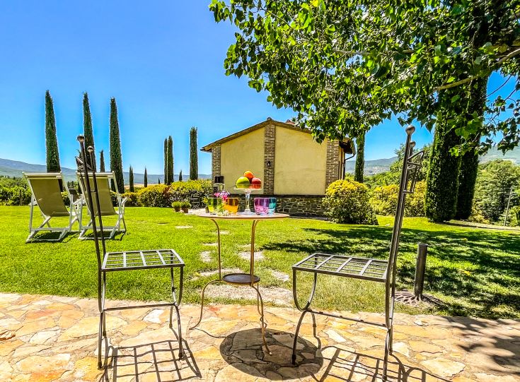 Un angolo sereno di giardino, con vista su un edificio, perfetto per una pausa durante l'estate.