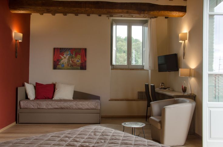 Hotel room with simple decor and a view of a surrounding green area.