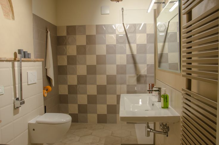 A modern bathroom featuring contemporary tiles and practical design, complete with a sink and toilet.