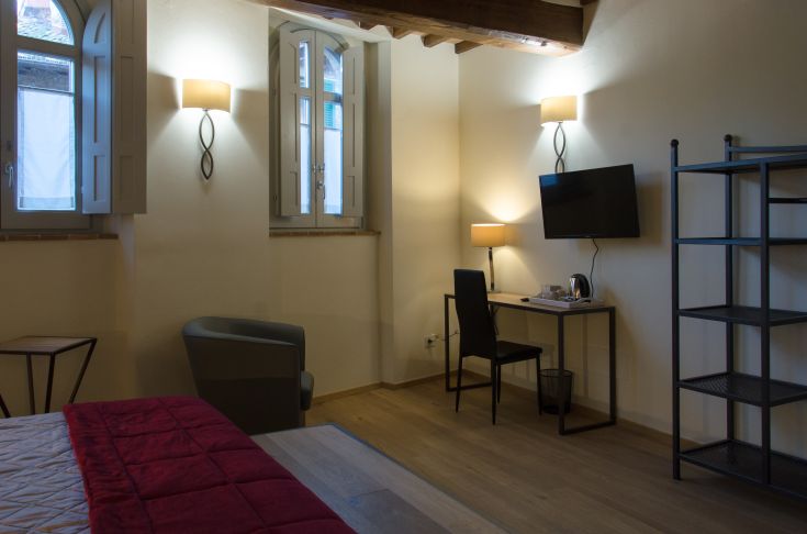 Cozy and bright hotel room with warm-toned furnishings in a building located in Paciano.