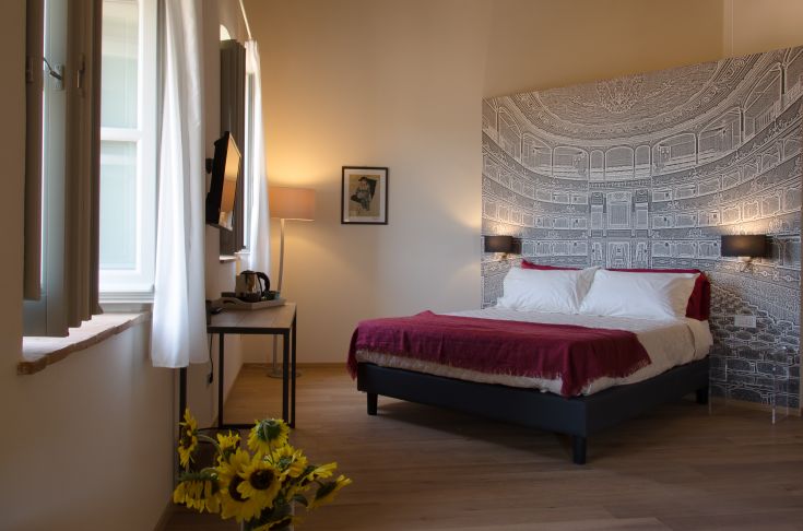 Elegant room with stylish furnishings, overlooking a blooming garden at the Boutique Hotel Antico Sipario.