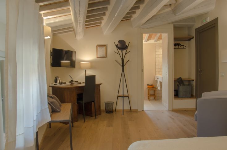 Antico Sipario Boutique Hotel room in Paciano, featuring essential furnishings and historic elements. Simple and functional.