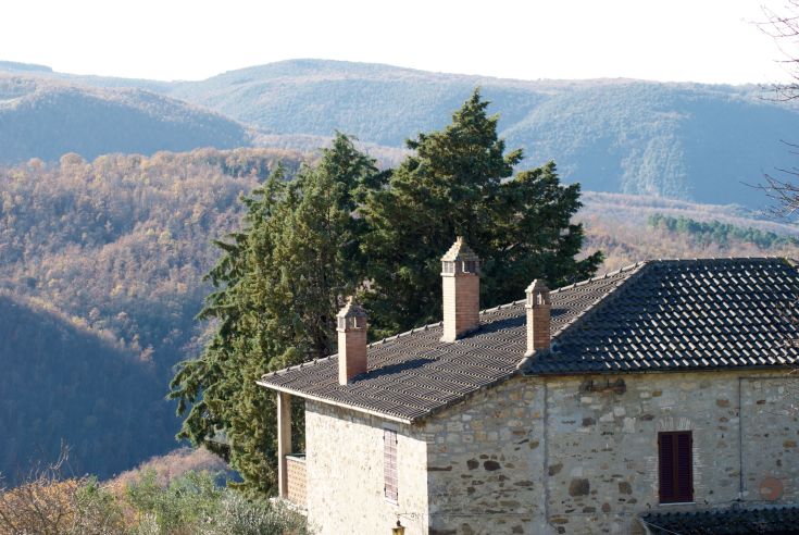 Ein Steingebäude, das zwischen Bergen und Bäumen liegt, eingebettet in eine ruhige Naturlandschaft.