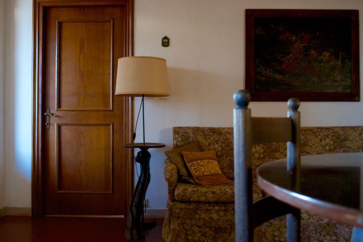 Innenbereich eines Bauernhauses mit einem blumigen Sofa, einer Lampe und einer Holztür. Eine gemütliche und angenehme Umgebung.