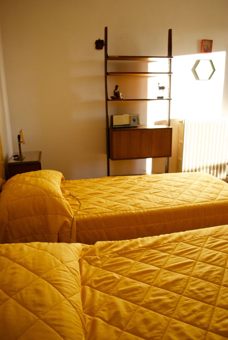 Praktisches Zimmer mit zwei Einzelbetten und gelber Bettwäsche. Einfach gestaltete Einrichtung.