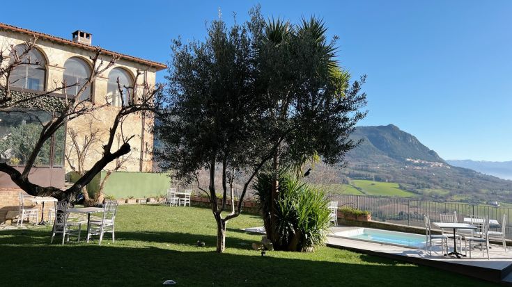 Une salle de bain simple avec une baignoire jacuzzi, des bougies allumées et une vue sur les collines environnantes, idéale pour des moments de tranquillité.