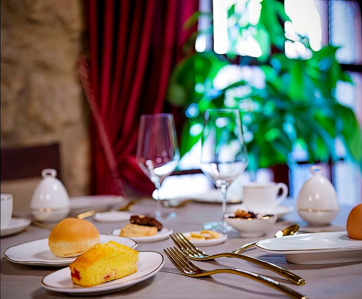 Petit déjeuner servi dans un environnement soigné, avec des plats simples et des desserts disposés sur une table.