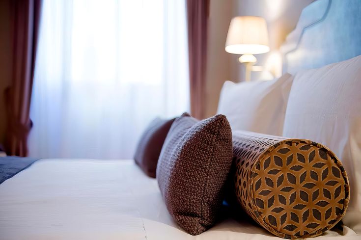 Une chambre simple et confortable avec des coussins décoratifs sur le lit.