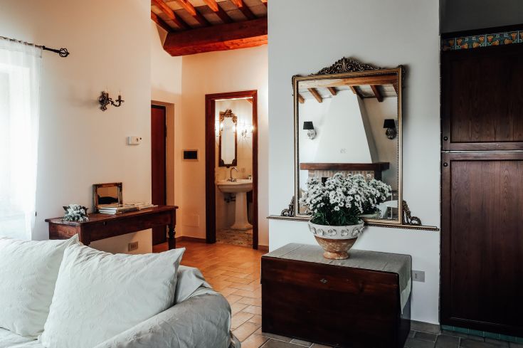 Spacious living room with simple furniture and rustic details, enhanced by fresh plants and flowers.