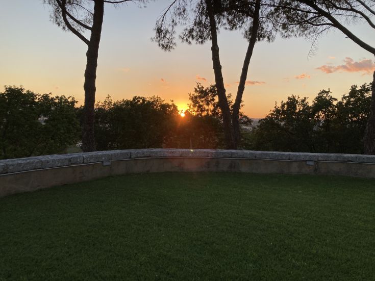 Un coucher de soleil paisible avec des arbres et une pelouse verte, reflétant la douceur de la campagne ombrienne.