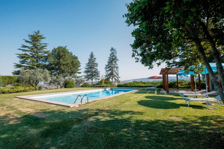 Une piscine immergée dans la verdure de l'Ombrie, entourée d'arbres créant une ambiance paisible.