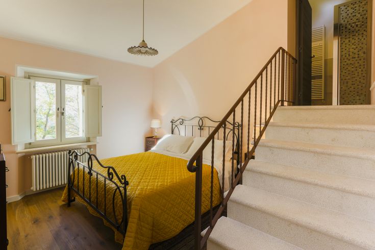 Chambre simple avec lit confortable et escalier dans un environnement détendu et lumineux.