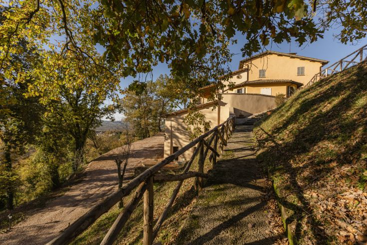 Une ferme située dans un cadre naturel en Ombrie, entourée de verdure et d'arbres.