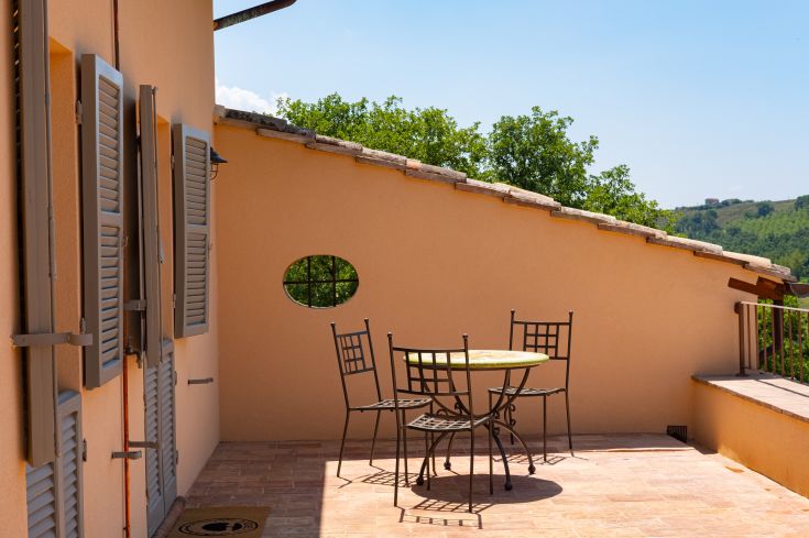 Terrasse ensoleillée avec une table et des chaises, entourée de la végétation typique de l'Ombrie.
