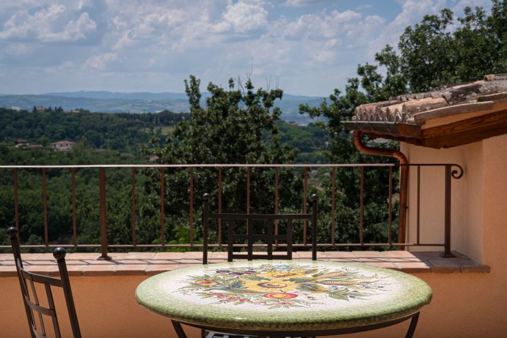 Une table colorée dans un environnement serein, avec une vue sur des collines verdoyantes et un paysage montagneux.
