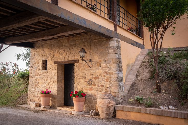 Une façade en pierre ornée de fleurs colorées qui reflète le charme de la campagne ombrienne.