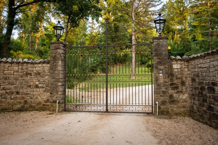 Un portail en bois menant à un parc entouré d'arbres typiques de l'Ombrie.