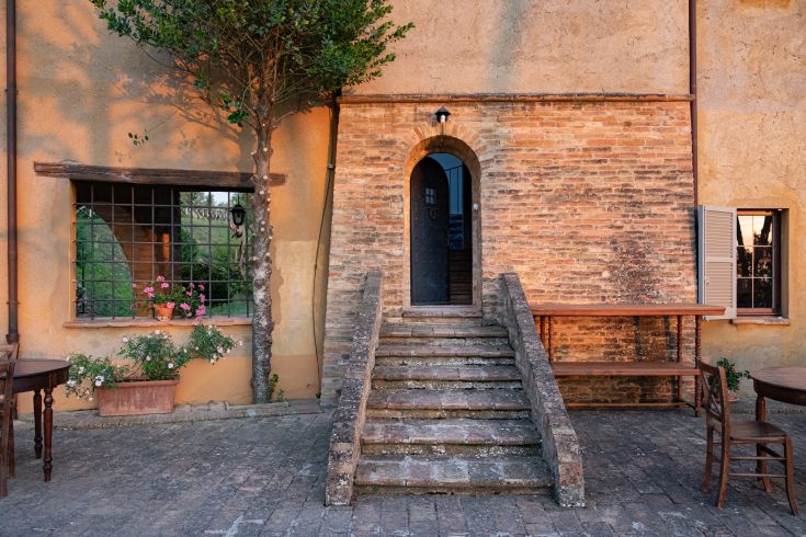 Une maison de campagne simple avec un escalier en pierre, entourée par la nature de l'Ombrie.