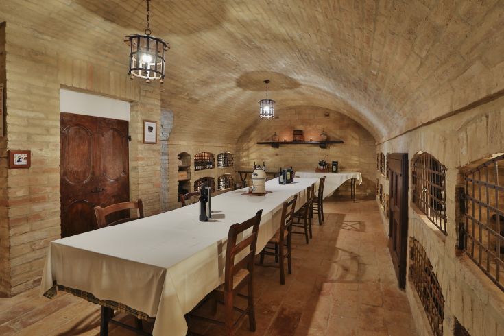 Une cave avec des murs en briques et une longue table, idéale pour des événements de dégustation de vins.
