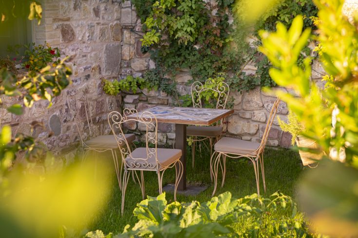 Un tavolo e sedie semplici sono sistemati in un'area verde, circondati da piante varie, ideale per il relax.