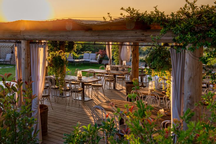 Un accogliente ristorante all'aperto durante il tramonto, con luce calda e colori tenui nell'aria.