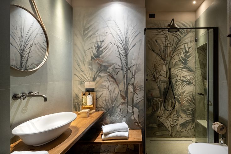 Un bagno moderno con pareti decorate da piante, lavabo semplice e doccia in vetro.