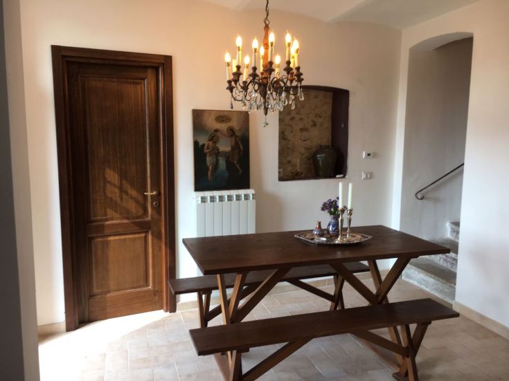 A simple dining room with a wooden table and chandelier, bright and inviting atmosphere.