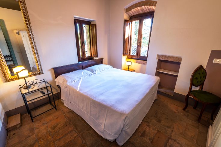 A simple room with Umbrian-style furnishings and large windows allowing plenty of natural light.