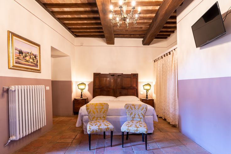 Serene room with simple furnishings and exposed beams. Calm atmosphere in a typical Umbrian farmhouse.
