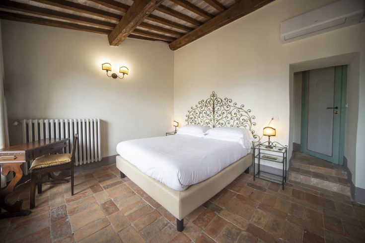 Comfortable room with a double bed, featuring stone and wood elements. A space ideal for a relaxing stay.