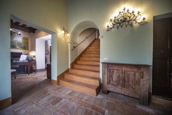 Entrance of a recently restored farmhouse, featuring wooden stairs and simple architectural details.