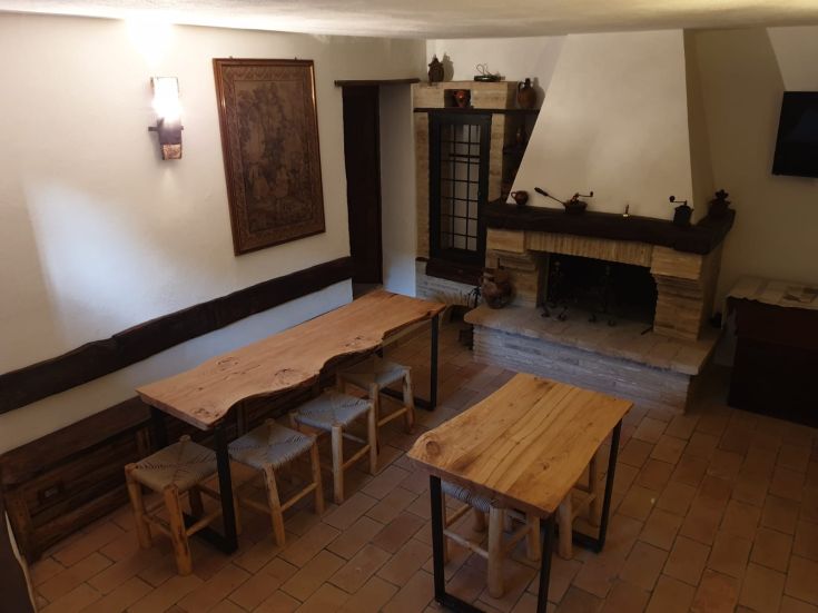 Spazio intimo con tavoli in legno e un camino, adatto per momenti di tranquillità.