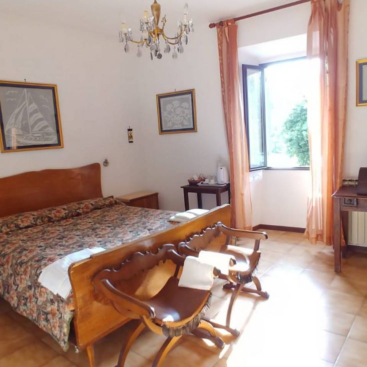 Camera luminosa con letti in legno, dotata di arredo semplice e finestre ampie.