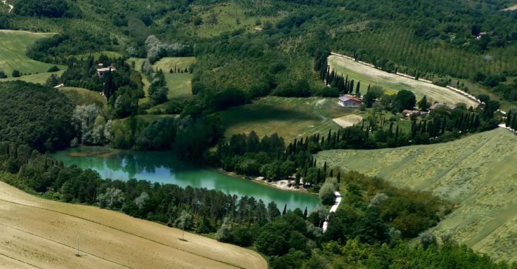 A countryside landscape featuring a lake surrounded by trees and lush vegetation, providing a serene atmosphere.