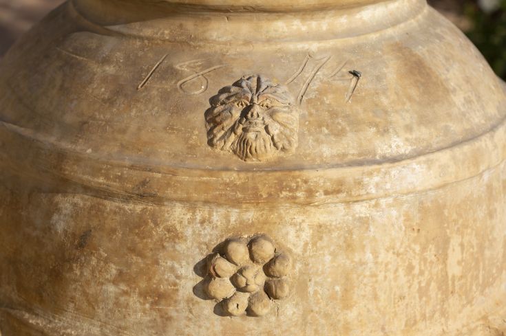 Detail of a vintage design vase decorated with faces and grape cluster motifs.