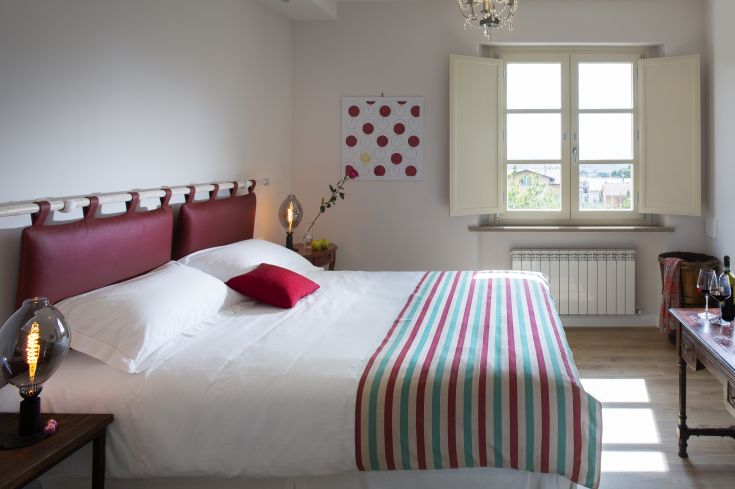 Cozy and well-lit room featuring a large bed and simple decorative elements.