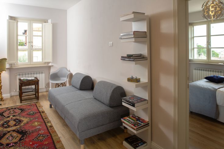 A bright and cozy living room with a gray sofa and a bookshelf.