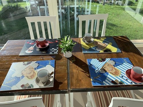 A beautifully set table in a bright room, adorned with paintings and green plants.