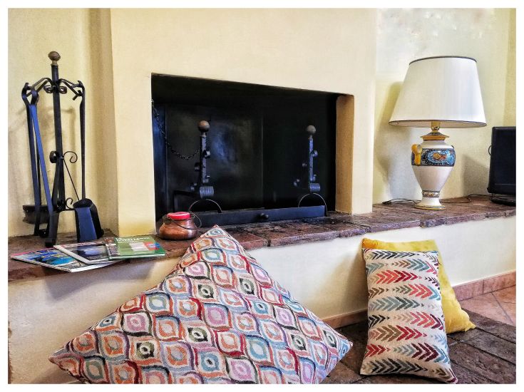 Un soggiorno comodo con cuscini dai diversi colori e un camino, ideale per trascorrere momenti di relax.