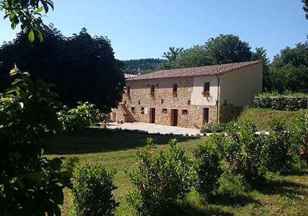 A farmhouse converted from an old mill, surrounded by nature and lush greenery.