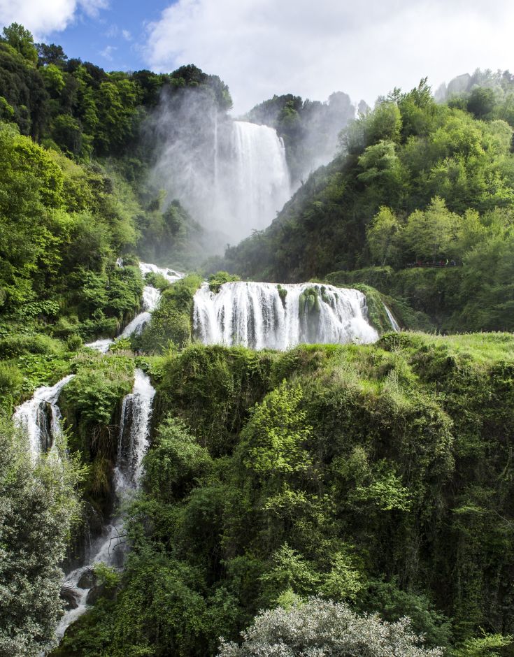 A view of waterfalls surrounded by lush greenery and vibrant vegetation.